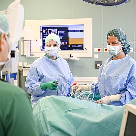 Drei Personen aus der Chirurgie operieren Patienten | Großer Monitor im Hintergrund | Foto@Karsten Klama