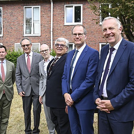 Sechs Männer stehen nebeneinander vorm DIAKO