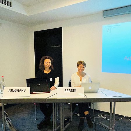 Dr. Junghans und Susanne Zebski mit Laptop am Tisch sitzend